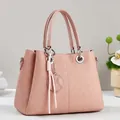 Detail of pink handbag featuring embossed geometric texture and soft tassel charm pendant - Pink