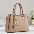 Detail of embossed geometric pattern and round metal pendant on beige tote bag - Khaki