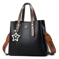 Black leather bucket bag with star charm and striped woven wide shoulder strap - Black