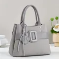 Detail of dark gray handbag featuring geometric embossing and a large rhinestone buckle - Gray