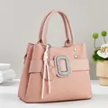 Close-up of geometric textured pink handbag with rhinestone buckle and tassel detail - Pink