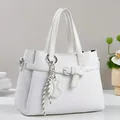 Dettaglio borsa tote bianca con trama a rilievo, fibbia decorativa e ciondolo a righe - Bianco Sporco