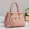 Detail of pink tote bag showing geometric embossing, gold hardware, and heart tassel - Pink