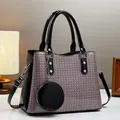 Close-up of pink woven shoulder bag with black leather straps and round coin purse accessory - Pink