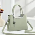 Détail d'un sac à main en cuir vert menthe avec garniture argentée et pendentif cœur - Vert