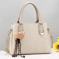Beige woven texture handbag with shoulder strap and plush bear charm on grey background - Khaki