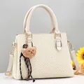 Detailed view of beige textured shoulder bag with plush bear charm and sunflower accent - Off White