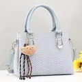 Dettaglio della borsa in maglia grigio-blu con manici in pelle e dettagli dorati - Blu