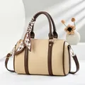 Elegante bolso Boston beige con ribete marrón y bufanda de pata de gallo sobre fondo - Albaricoque