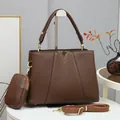 Détail macro du sac à main en cuir marron foncé avec logo en V doré élégant - Café