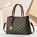 Detail of vintage tote bag showing color-block patterns and gold flower charm - Black
