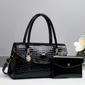 Detail der schwarzen Handtasche mit Krokoprägung, Löwenanhänger und passender Geldbörse - Schwarz