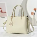 Elegante cremefarbene Handtasche aus Kunstleder mit Lychee-Narbung und Goldanhänger - Cremeweiß