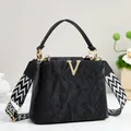 Minimalist black tote bag with gold V hardware and a wide geometric shoulder strap - Black
