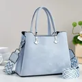 Detail der hellblauen Nubuk-Handtasche mit silbernen Anhängern und breitem Schultergurt - Blau