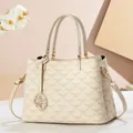Cream vintage handbag with pink geometric patterns and floral charm on warm background - Solid White