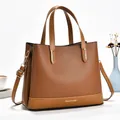 Detailed view of brown lychee-grain leather tote bag with gold hardware and removable strap - Earthy Yellow