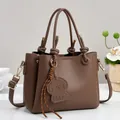Deep brown litchi pattern leather handbag with teddy pendant and golden hardware - Coffee