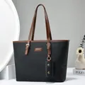 Classic black leather tote bag with brown handles and a mini charm in a home setting - Black