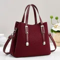 Detail of burgundy leather handbag with V-shaped woven texture and silver hardware - Burgundy