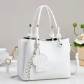 Detail of white litchi pattern leather handbag with knotted handles and dog charm - White