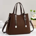 Detail of dark brown tote bag with woven texture, dual handles and silver metal accents - Coffee
