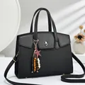 Detail of black tote with quilted texture, metal twist lock and star charm pendant - Black