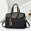 Detail of black crossbody bag featuring heart lock, star charm, and woven texture - Black