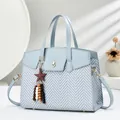 Detail of light blue crossbody bag with herringbone weave, gold lock, and star pendant - Blue