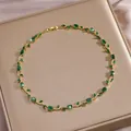 Detaillierte Nahaufnahme der goldenen Rebenkette mit grünen Zirkonia-Blättern - Smaragdgrüner Edelstein-Rebenhalsketten-Stil (XL-3385)