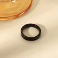 Macro shot of minimalist 4mm polished black stainless steel ring on a beige surface - US 6 / Black