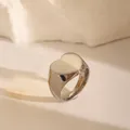 Close-up of heart-shaped stainless steel signet ring on textured stone surface - US 6