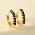 Close-up of gold hoop earrings with pavé set black stones on a beige geometric stand - Black Hoop