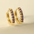 Detailed close-up of golden huggie earrings with sparkling purple zircon stones - Purple Hoop