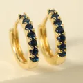 Close-up of gold plated hoop earrings with channel-set round blue zircon gemstones - Dark Blue Hoop