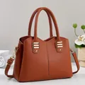 Elegante karamel lederen handtas met lychee textuur en gouden metalen accenten - Aardgeel