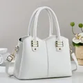 Close-up of white lychee textured leather handbag with elegant gold metal buckles - White