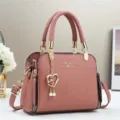 Dettaglio borsa in pelle rosa a grana litchi con scritte dorate e ciondolo a cuore - Rosa