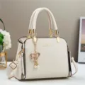 Minimalistische beige Lederhandtasche mit goldenen Beschlägen und Perlenherz-Anhänger - Gebrochenes Weiß