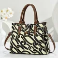 Modern canvas tote bag with black geometric print and brown leather handles on white background - Black
