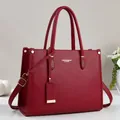 Detail of burgundy pebbled leather tote with golden hardware and fashion lettering - Red