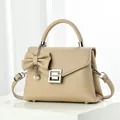 Detail view of apricot lychee pattern leather handbag with silver geometric lock and bow - Khaki