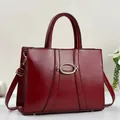 Detail view of burgundy leather handbag showing polished surface and metallic oval buckle - Burgundy