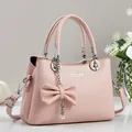 Détail d'un sac à main en cuir grainé rose clair avec nœud et décorations en perles - Rose