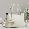 Detalle de bolso en cuero crema con colgante de perla y letras metálicas de moda - Blanco Roto