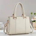 Detail der cremeweißen Handtasche mit geflochtener Struktur und goldener Hardware - Weiß