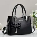 Black litchi pattern leather handbag for women featuring a bow and pearl charm - Black