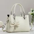 Cremeweiße Handtasche aus Leder mit Litschi-Struktur, Perlenanhänger und Silberbeschlägen - Weiß