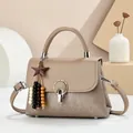 Elegant apricot flap handbag with wooden star charm and silver lock in minimalist setting - Khaki