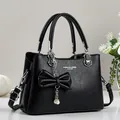 Elegant black lychee texture leather handbag with bow pendant and pearl details - Black